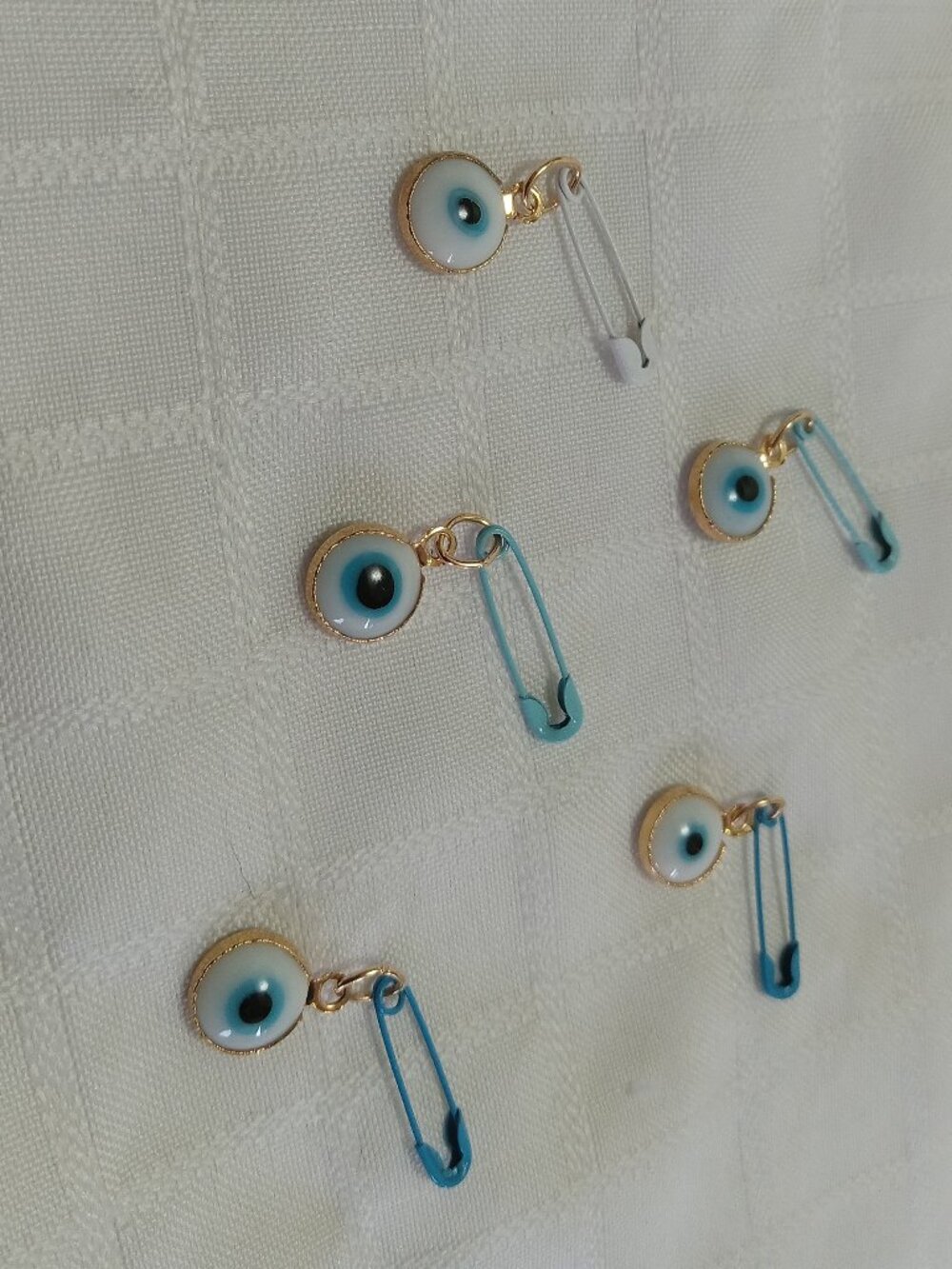 Five handmade tiny evil eyes on a safety pin